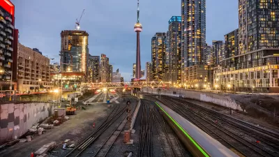 Looking down train trains in downtown Toronto, Canada with CN Tower in background.