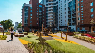 High-rise modern apartment buildings with green space in front courtyard with outdoor exercise equipment.