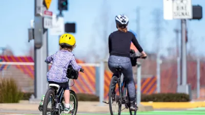 Mother and child on bicycles riding on green dedicated bike lane