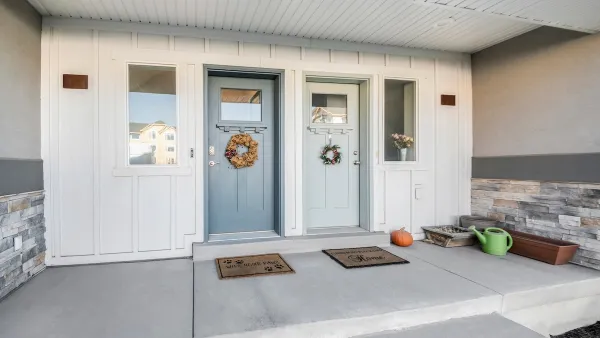 Two pastel green/blue front doors on duplex with decorative wreaths.