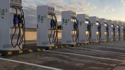 Row of white electric vehicle chargers in an outdoor parking lot.