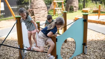 Group of three children playing on playground equipment.