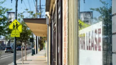 Close-up of For Lease sign in window of shop storefront with city sidewalk and vintage street light in background.
