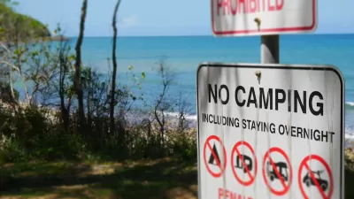 "No Camping" sign with symbols on a beachfront.