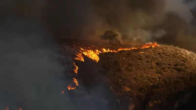 Line of wildfire moving across dry hillside in Malibu, California during 2018 Woolsey fire.