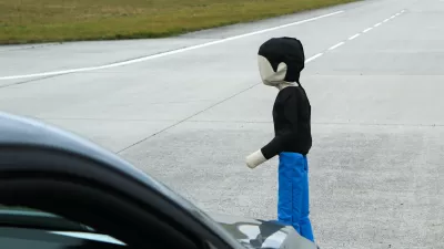 Child-sized pedestrian crash test dummy in front of car being tested