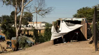 Makeshift shelter built by unhoused people on hillside overlooking freeway in Stockton, California.