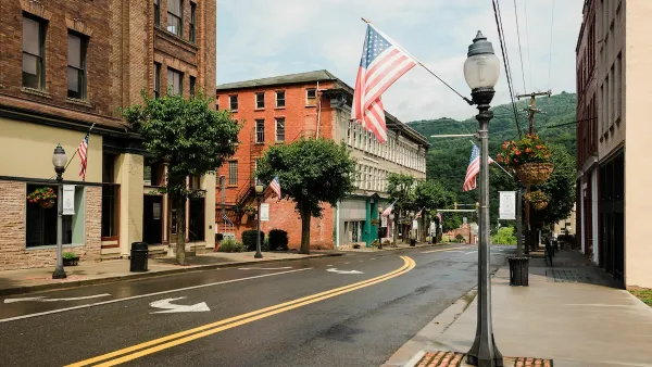 Street with historic buildings and American flag hanging from lamppost in downtown Hinton, West Virginia.