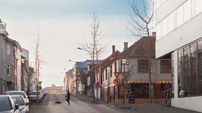 Empty street in Reykjavik, Iceland with man walking dog in crosswalk.