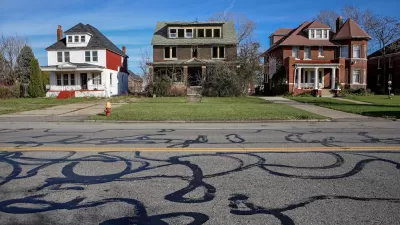 Three two-story houses on residential street in Detroit, Michigan. Center house appears abandoned.