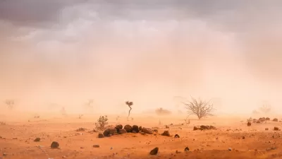 Dusty desert landscape with low visibility and few scraggly plants.
