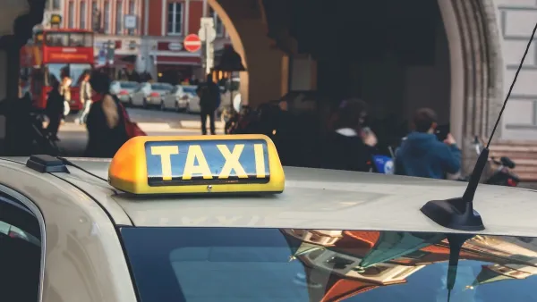 Close-up on yellow and black TAXI sign on top of beige car in central Munich, Germany.