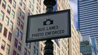 Close-up of "Bus Lanes - Photo Enforced" sign with camera logo on New York City street pole.