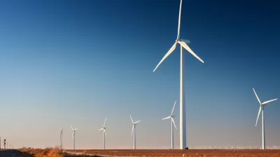 Row of white wind turbines in wide open dirt field in west Texas.