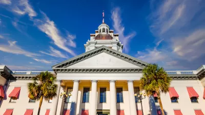 White and peach Florida state capitol building with palm trees in front in Tallahassee, Florida.