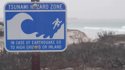 Close-up of blue and white tsunami warning sign on coast in Monterey, California on gloomy day.