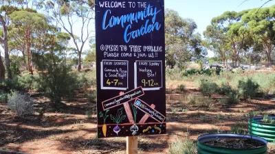 Chalkboard sign at front of a community garden with hours and information.