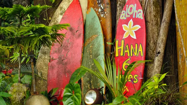 Red and yellow surfboards leaning against fence in Maui, Hawaii.