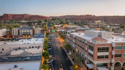 Aerial view of wide street in St. George, Utah at dusk with red rock mountains in background.