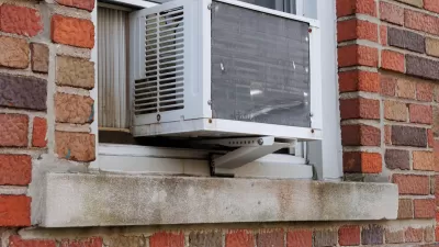 Close-up of window-mounted air conditioning unit on outside of red brick building