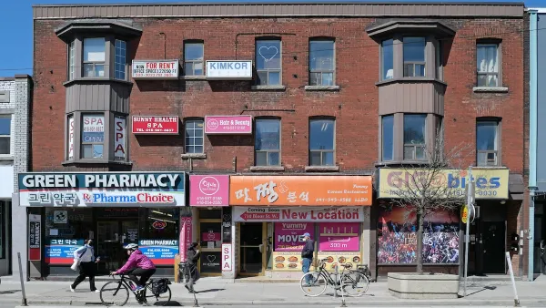 Two-story red brick buildings and street with bike lane in Toronto, Canada.