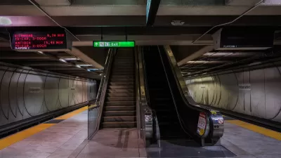 Empty underground Muni train platform in San Francisco with escalator, stairs in center of image.