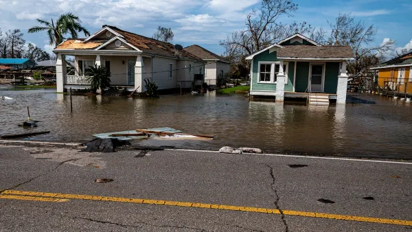 Two small wooden one-story homes in Florida with floodwaters at their doors.