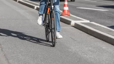Close-up of person on road bike riding on protected bike lane separated by concrete curb from street.
