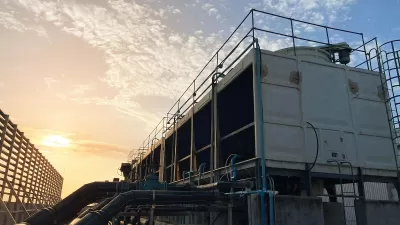Cooling tower on data center building roof against twilight sky.