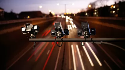 Three speed cameras aimed down at a busy freeway with blurred traffic at twilight.