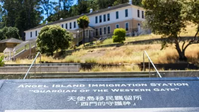 Close-up of plaque at Angel Island Immigration Station, California with historic building in background.