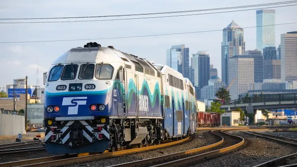 A blue and white Sound Transit heavy rail commuter trail with downtown Seattle skyline in background.