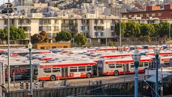 Red and white Muni buses parked in a yard in San Francisco, California.