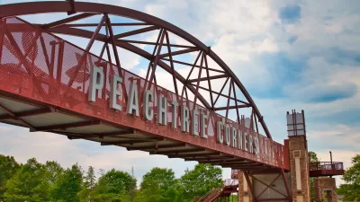 Red bridge with arches over highway with white letters spanning bridge "Peachtree Corners" near Atlanta, Georgia