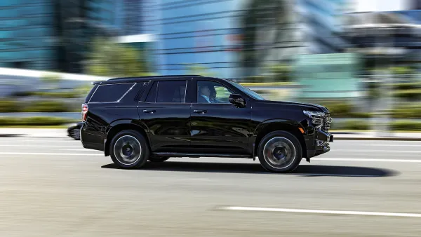 Large black SYV driving down city street with blurred background.