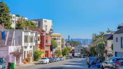View down San Francisco street with colorful residential buildings and high-rise downtown buildings in distance.