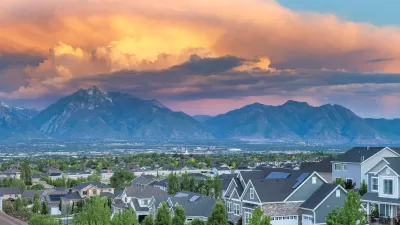 View of residential neighborhood with large homes with tall mountains and cloudy sunset sky in background in Salt Lake City, Utah.