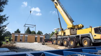 Modular home under construction with crane dropping in components.