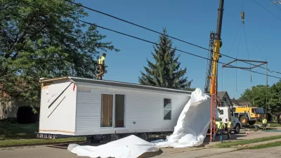 White modular home being installed on a lot.