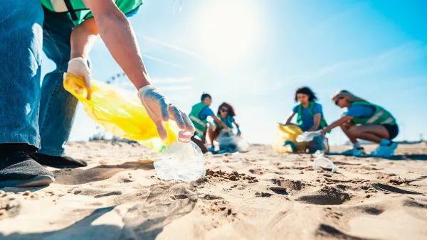 People at beach on sunny day doing clean-up of plastic bottles and other trash.