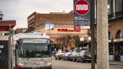Close-up of white and red Muni sign at bus stop on Polk Street in San Francisco, California with blurred bus in background.