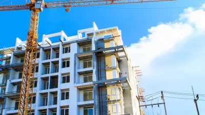 Multistory apartment building under construction with yellow crane.
