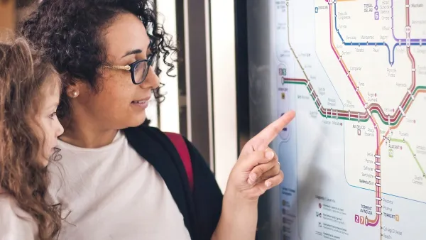 Woman and young girl looking at subway map, woman pointing.