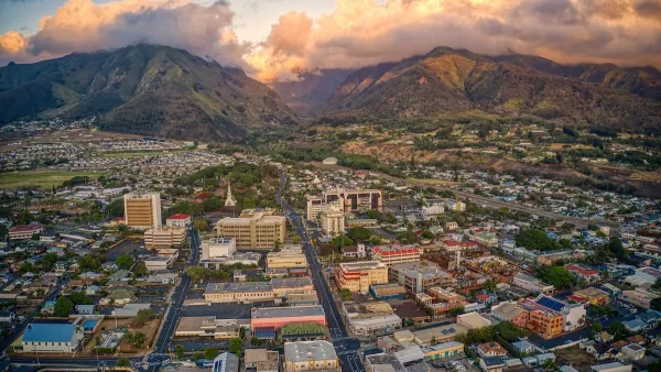 Aerial view of town of Wailuku in Maui, Hawaii with mountains in background against cloudy sunset sky.