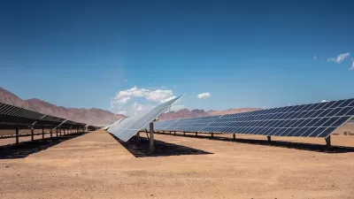 Rows of photovoltaic solar panels in the Nevada desert with mountains in background.
