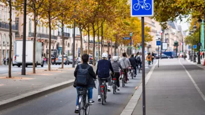 People on bikes ride on protected bike path along the Seine River in Paris, France