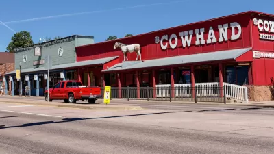 Single-story western-style buildings in Woodland Park, Colorado. Red building on corner labeled "COWHAND" in white text.