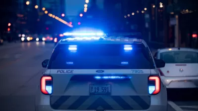 Chicago police car with blue lights on stopped on street in evening.