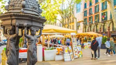 Close-up of decorative water fountain on La Rambla pedestrian street in Barcelona, Spain with blurred pedestrians in background.