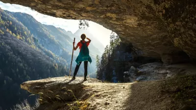 Woman stands on rock overlooking mountain valley.